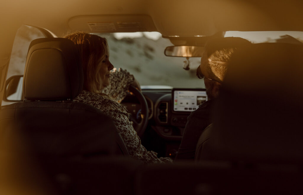 Couple sitting in driver and passenger seats in the car, listening to music.