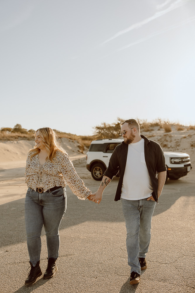 Couple walks through parking lot while holding hands