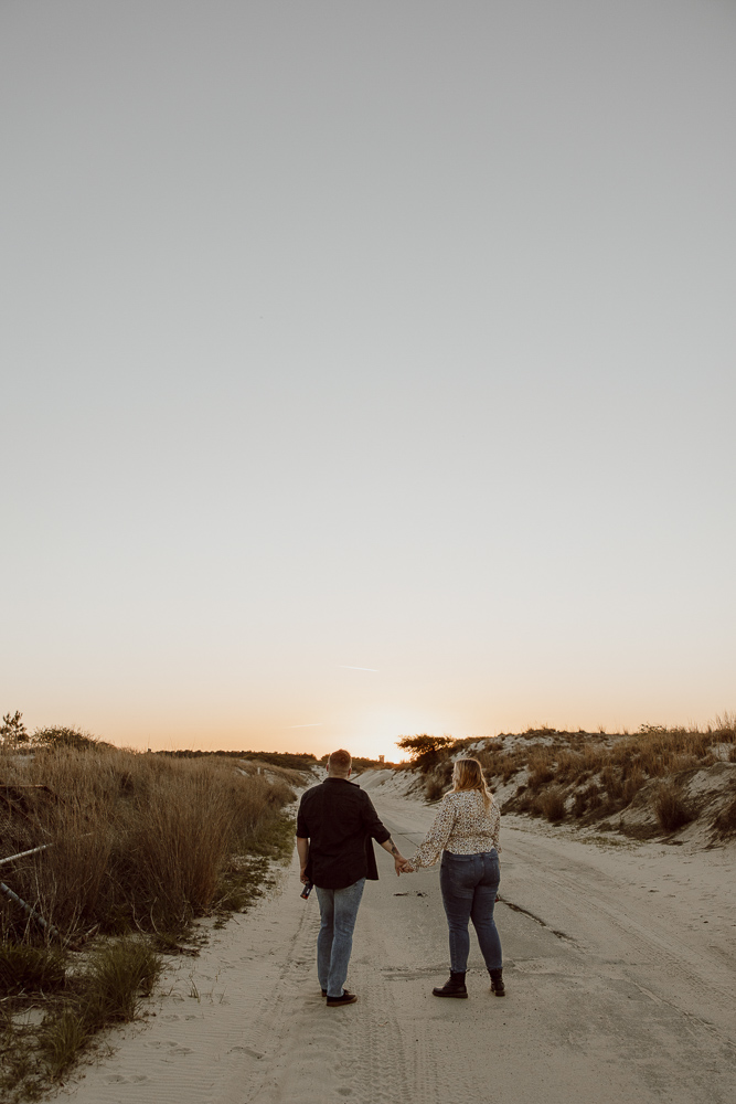 couple walks while holding hands as they watch the end of the sunset.