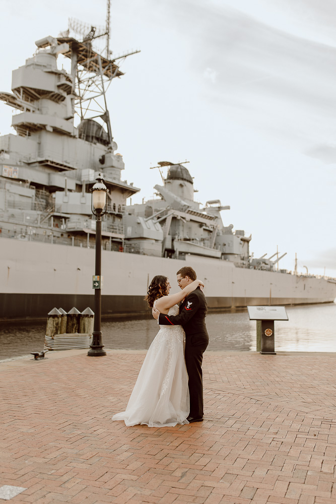 Military member and military spouse share their first dance in from of the USS Wisconsin in Norfolk Virginia.