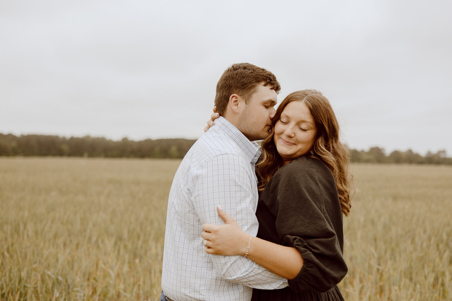 Couple holds each other close as he whispers in her ear.