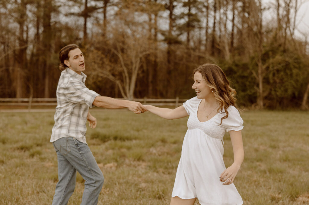 Couple spins in circles while holding hands in an open field.