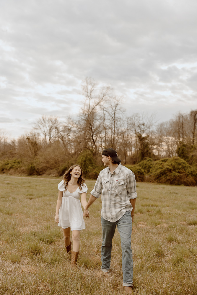 Couple holding hands while smiling and walking towards the camera.