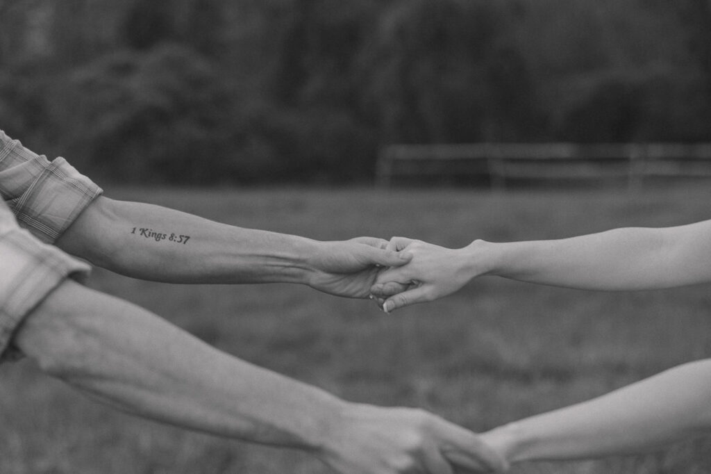 Close up photo of couple reaching out and holding hands.