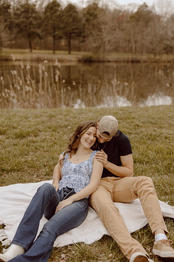 Couple cuddled up onto each other while sitting on a blanket.