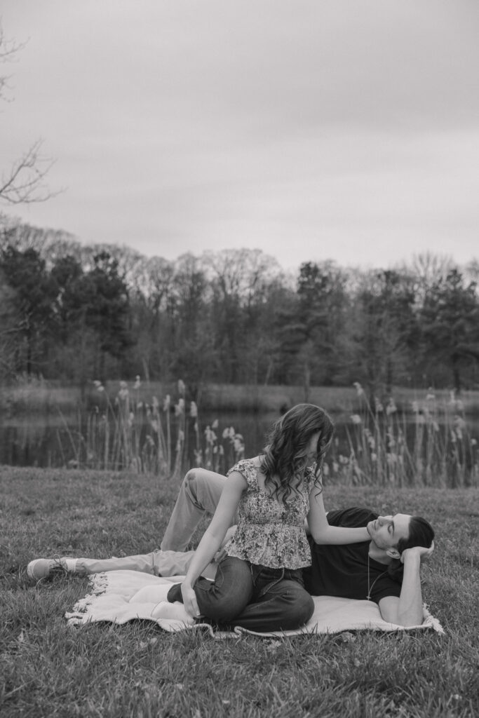 Couple relaxing on a blanket as she plays with his hair.