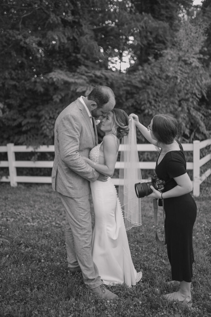 A photographer helps bride with her veil.