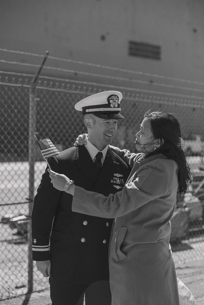 A navy sailor and his wife hug reuniting after a long deployment.