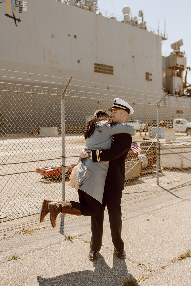 A navy sailor and his wife hug and spin after reuniting after a long deployment.