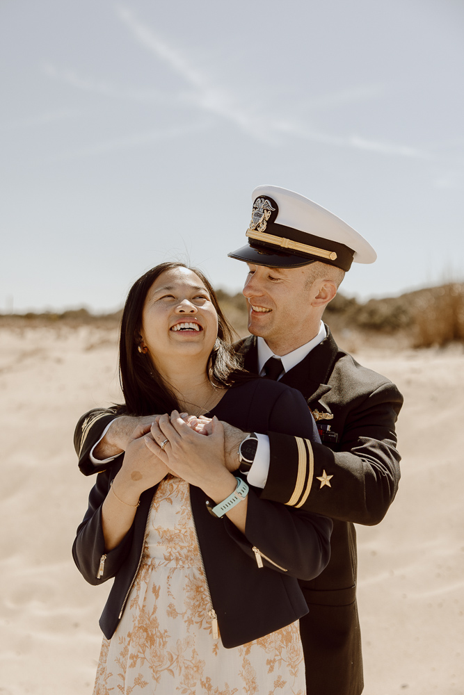 A Navy sailor and spouse wrap arms around each other and smile.