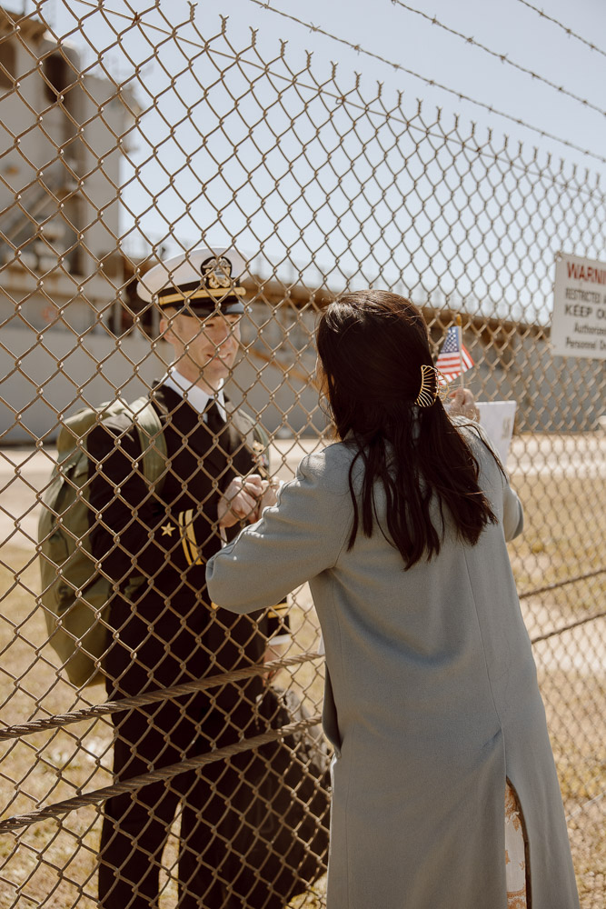 Navy sailor and his spouse reunite through fence.