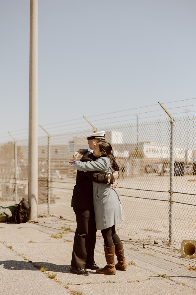 A navy sailor and his wife hug reuniting after a long deployment.