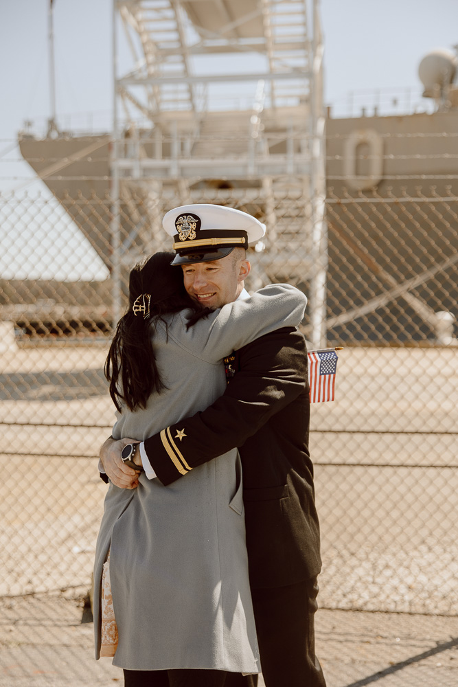 A navy sailor and his wife hug reuniting after a long deployment.