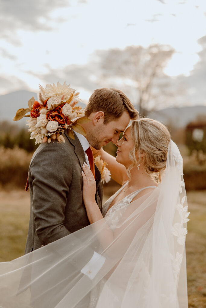 This image is of a wedding couple standing close to each other while their foreheads and noses touch.