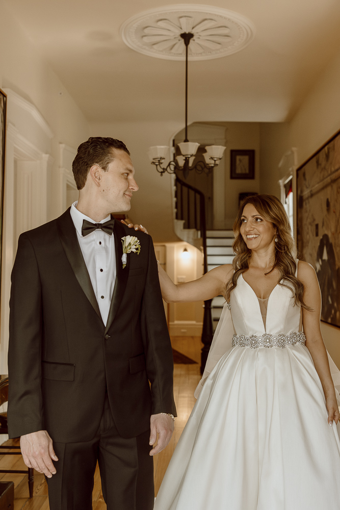 Bride taps on her grooms shoulder for him to turn and see her in her wedding dress.