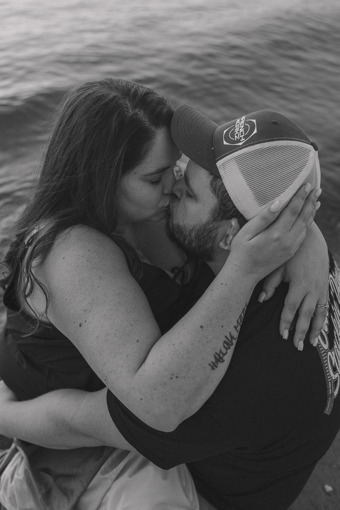 A couple kisses in the water at the beach and shares a kiss.