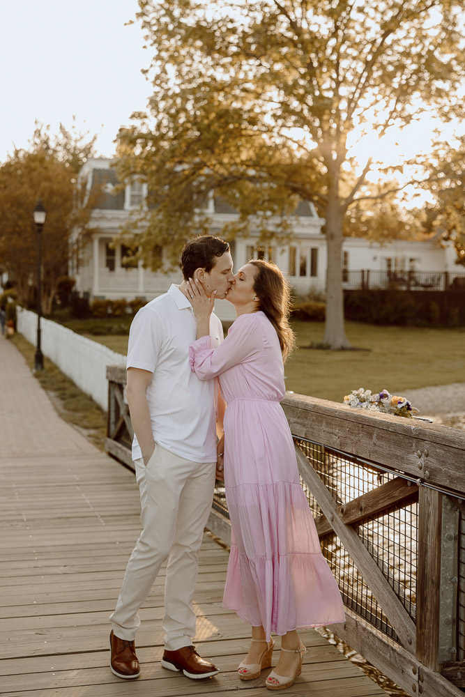 A couple shares a kiss on a walking pier during sunset at st. Michaels in Maryland.