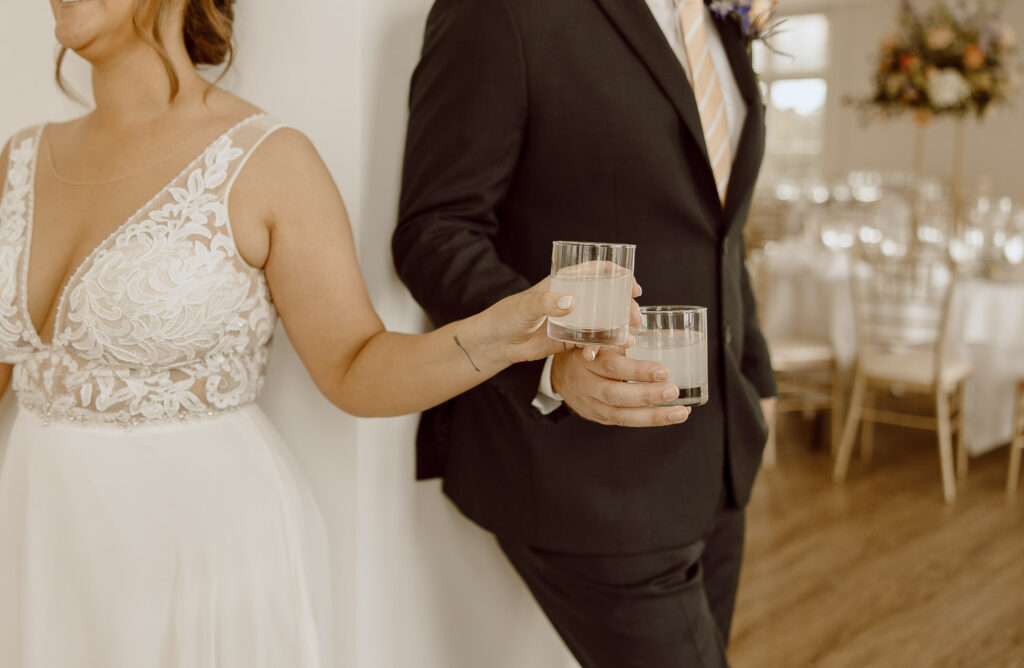 Bride and Groom hold a shot in their hands during their first touch on their wedding day